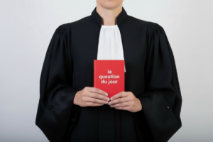 image d&eacute;corative g&eacute;n&eacute;r&eacute;e par IA pr&eacute;sentant une robe d'avocat tenant un petit livre rouge avec le texte la question du jour" sur la couverture
